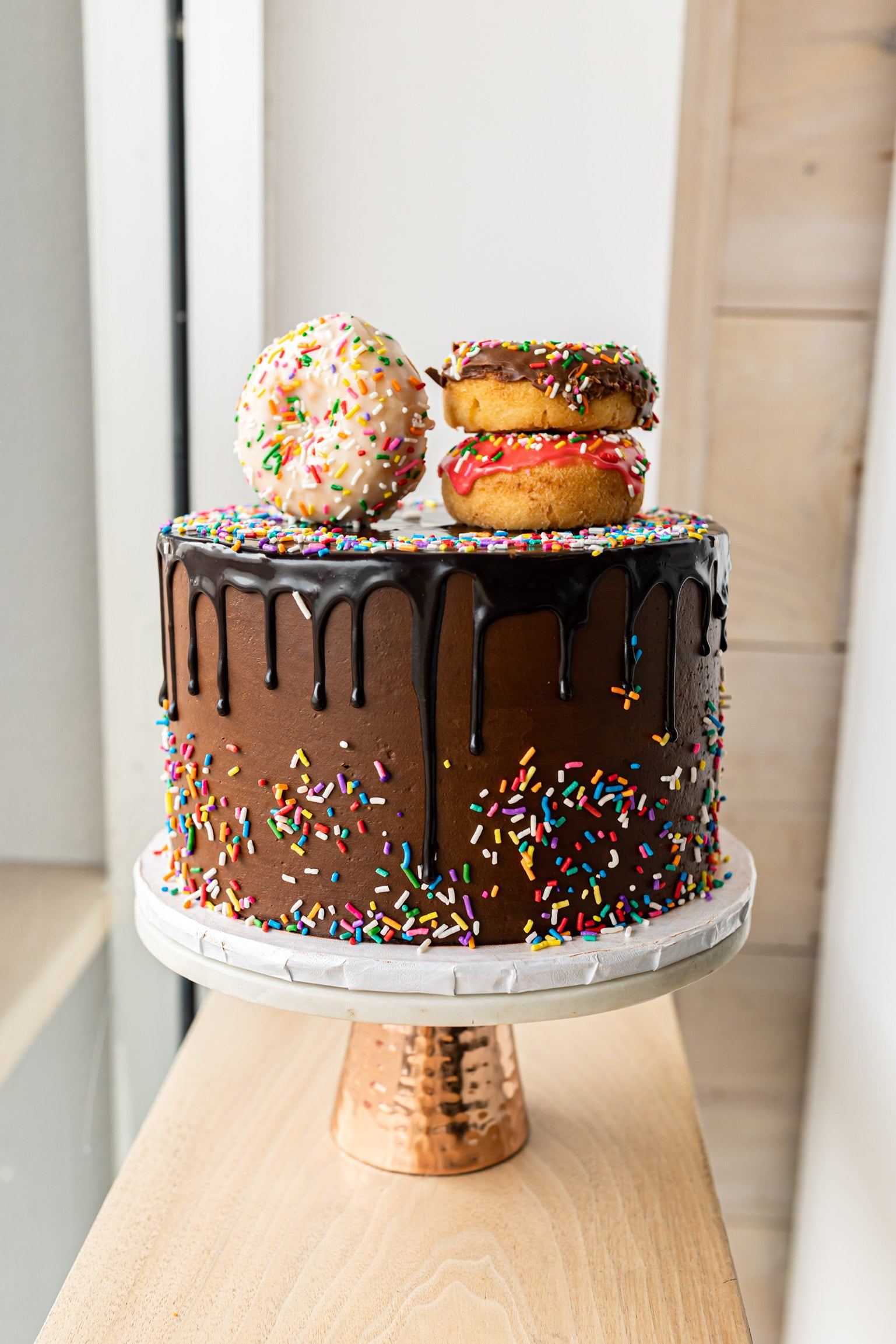 Vertical closeup shot of delicious Donut choco Birthday cake with donuts on  top and white drip Stock Photo - Alamy